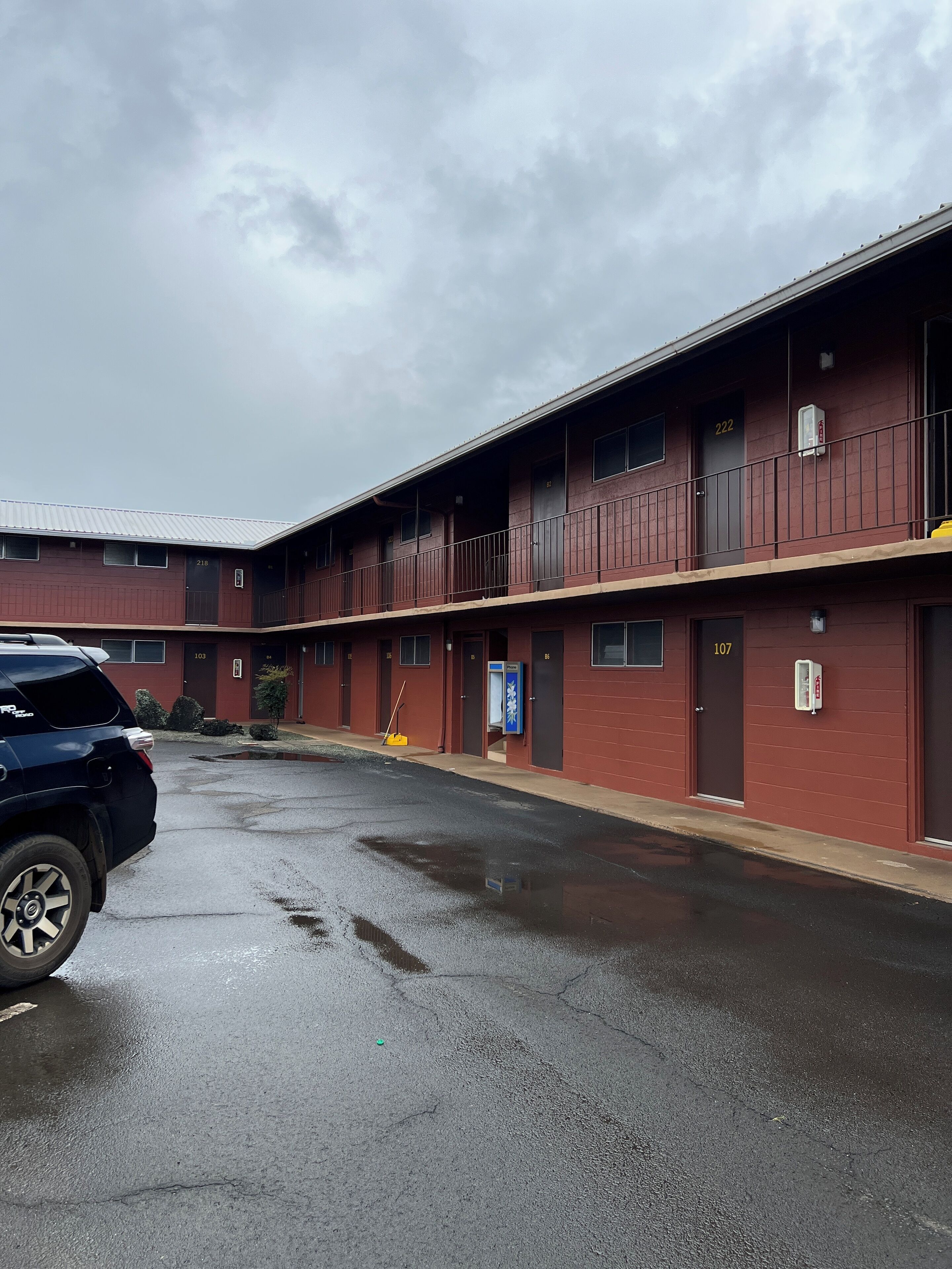 A multi-story motel with numbered rooms, a parking lot, and a wet road.