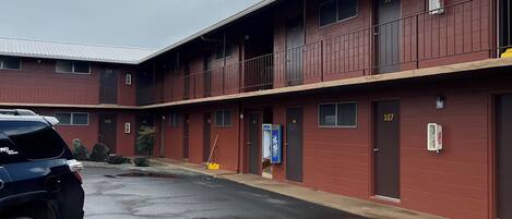 A multi-story motel with numbered rooms, a parking lot, and a wet road.