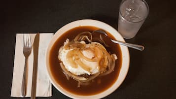 A bowl of soup with a spoon and a glass of water on a table.