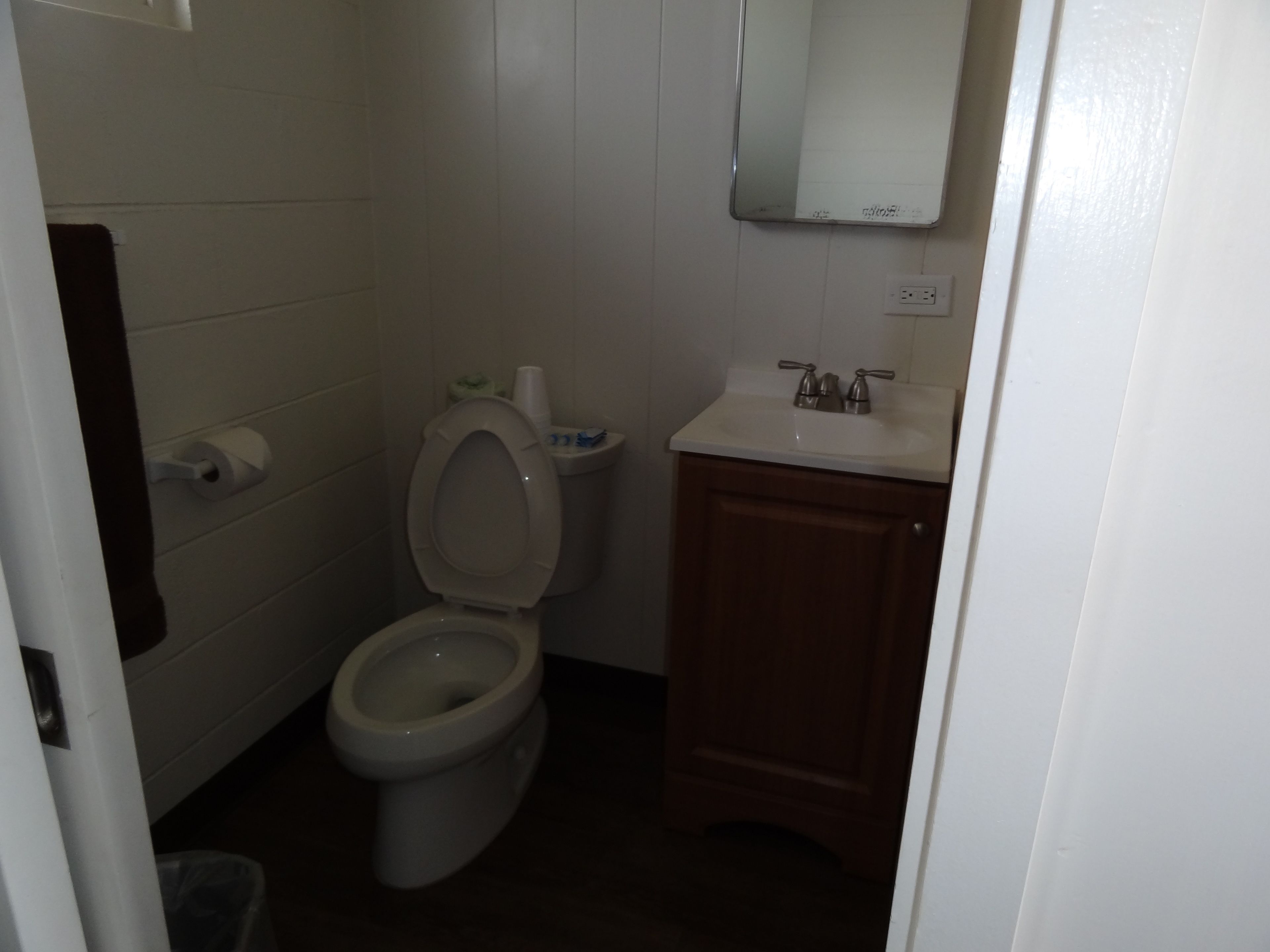 A small, clean bathroom with a toilet, sink, and mirror.