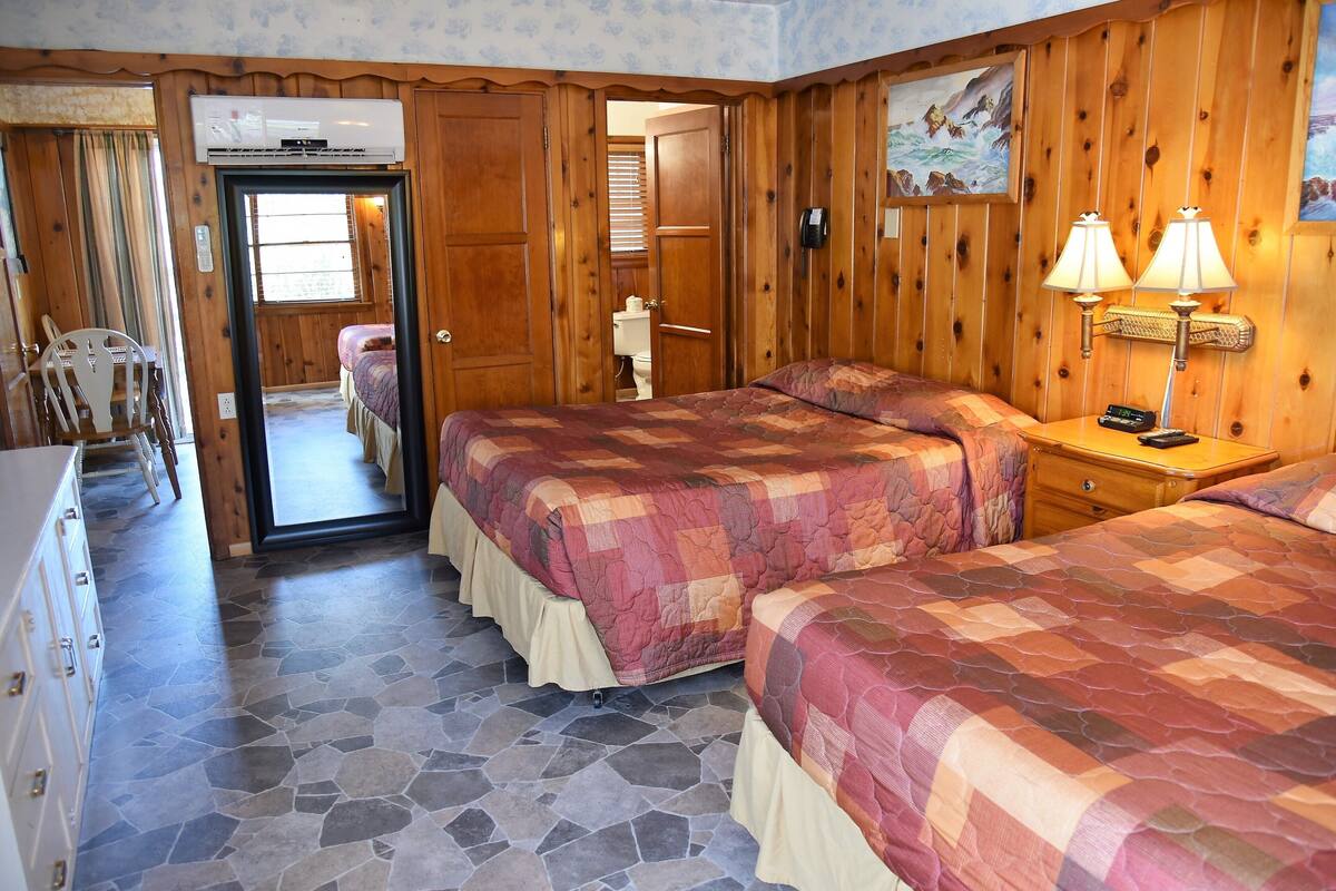 A room with two beds, a wooden wardrobe, a desk, and a chair.
