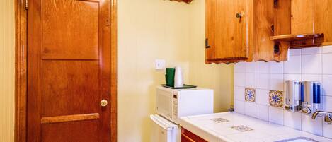 A compact kitchen with wooden cabinets, a white refrigerator, and a tiled backsplash.