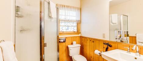 A bathroom with a shower, toilet, and sink.