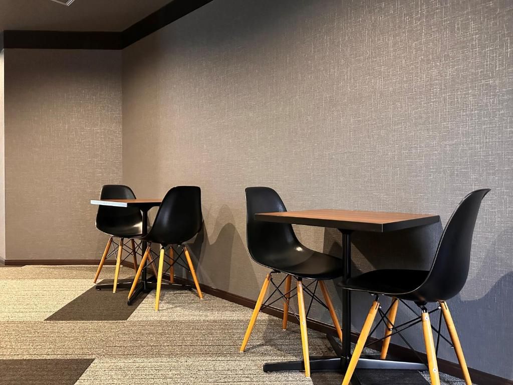 A conference room with a long table and four chairs, carpeted floor, and a textured wall.
