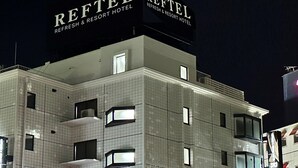 Un hotel de varios pisos con fachada de azulejos, ventanas iluminadas y un letrero que dice 'REFETEL'.