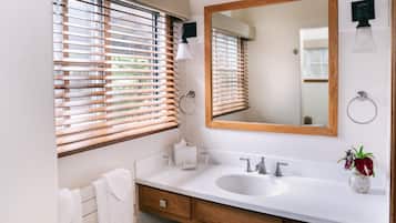 A bathroom with a white sink, wooden vanity, and a large mirror.