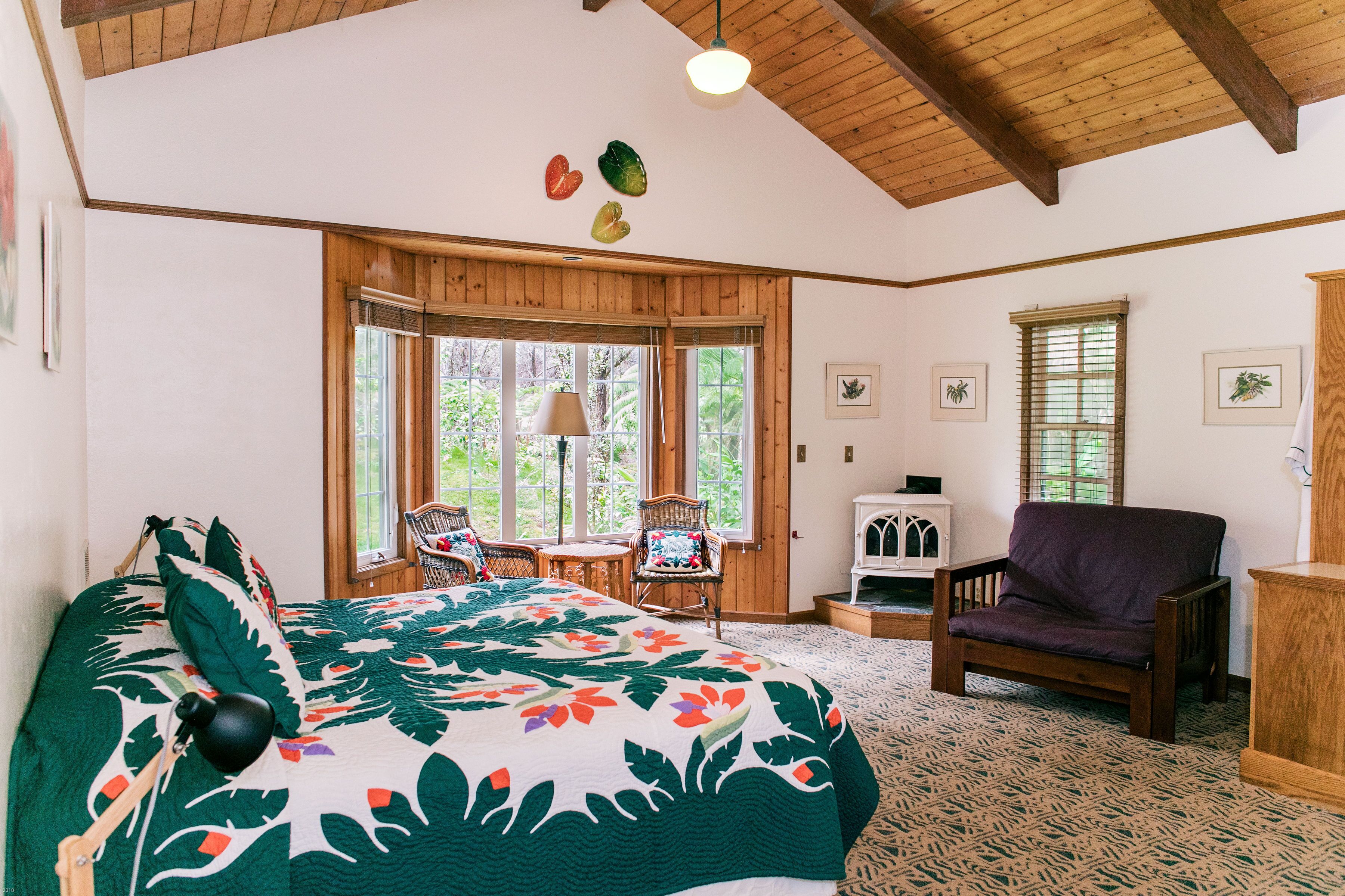 Une chambre avec un grand lit, un plafond en bois et une vue sur l’extérieur par une fenêtre.