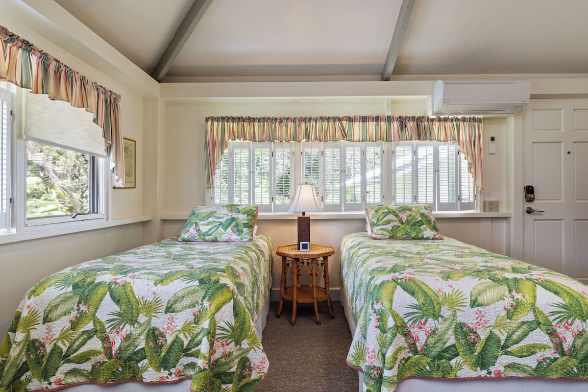 A room with two beds, a small table, and a window with curtains.