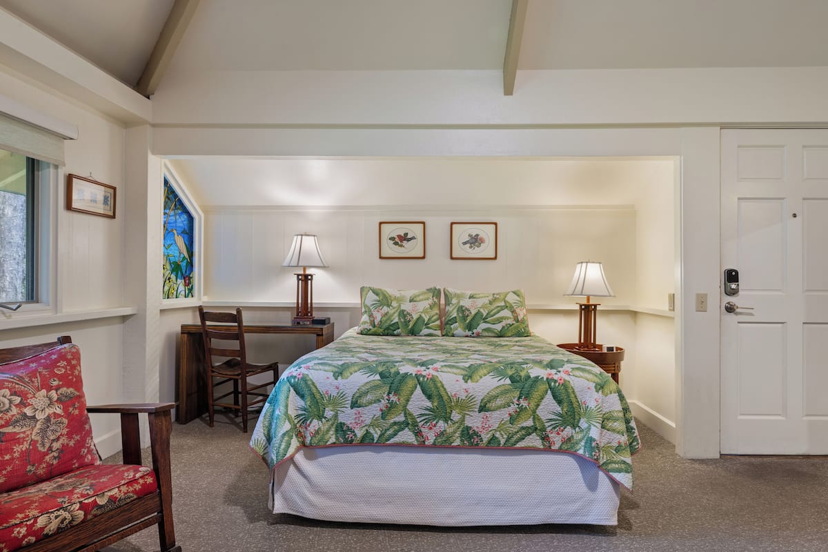 A bedroom with a bed, a chair, a desk, and a door.