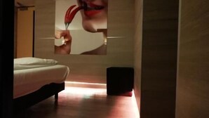 A modern hotel room with a bed, a small table, and a wall-mounted artwork.