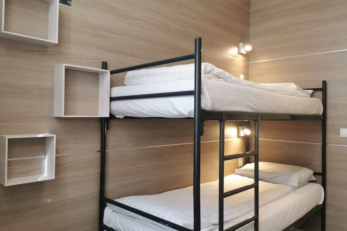 A bunk bed room with wooden walls and built-in shelves.