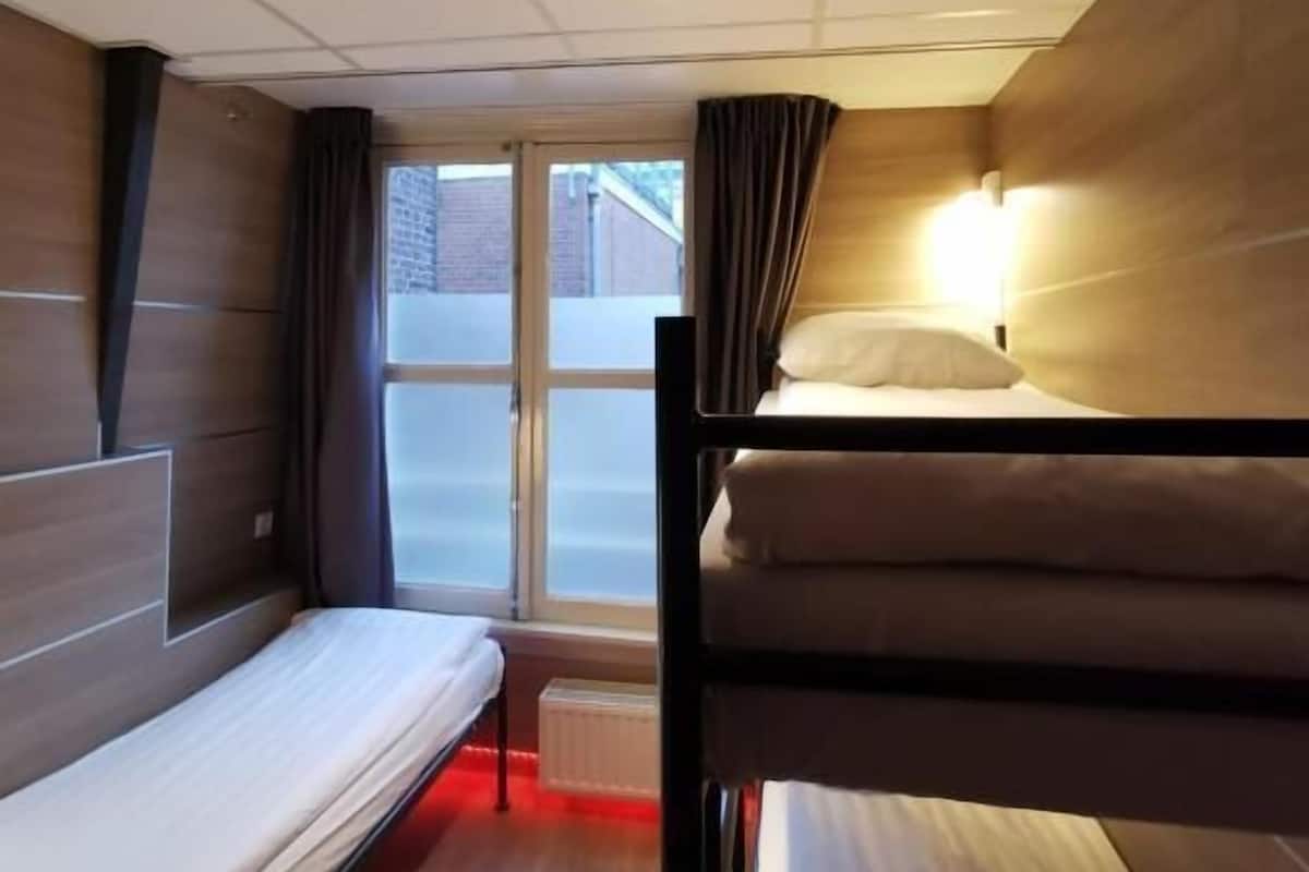 A room with bunk beds, a window with curtains, and a radiator.