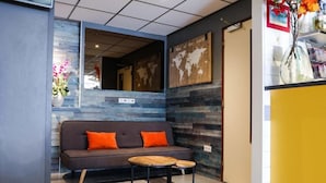 A modern reception area with a sofa, two small round tables, and a world map on the wall.
