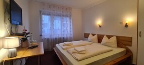 Ett hotellrum med en säng, ett sängbord, en lampa och en tv som är monterad på väggen.