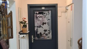 Un pasillo con una recepción, una puerta con panel de vidrio decorativo, una lámpara en el techo y suelo de baldosas.