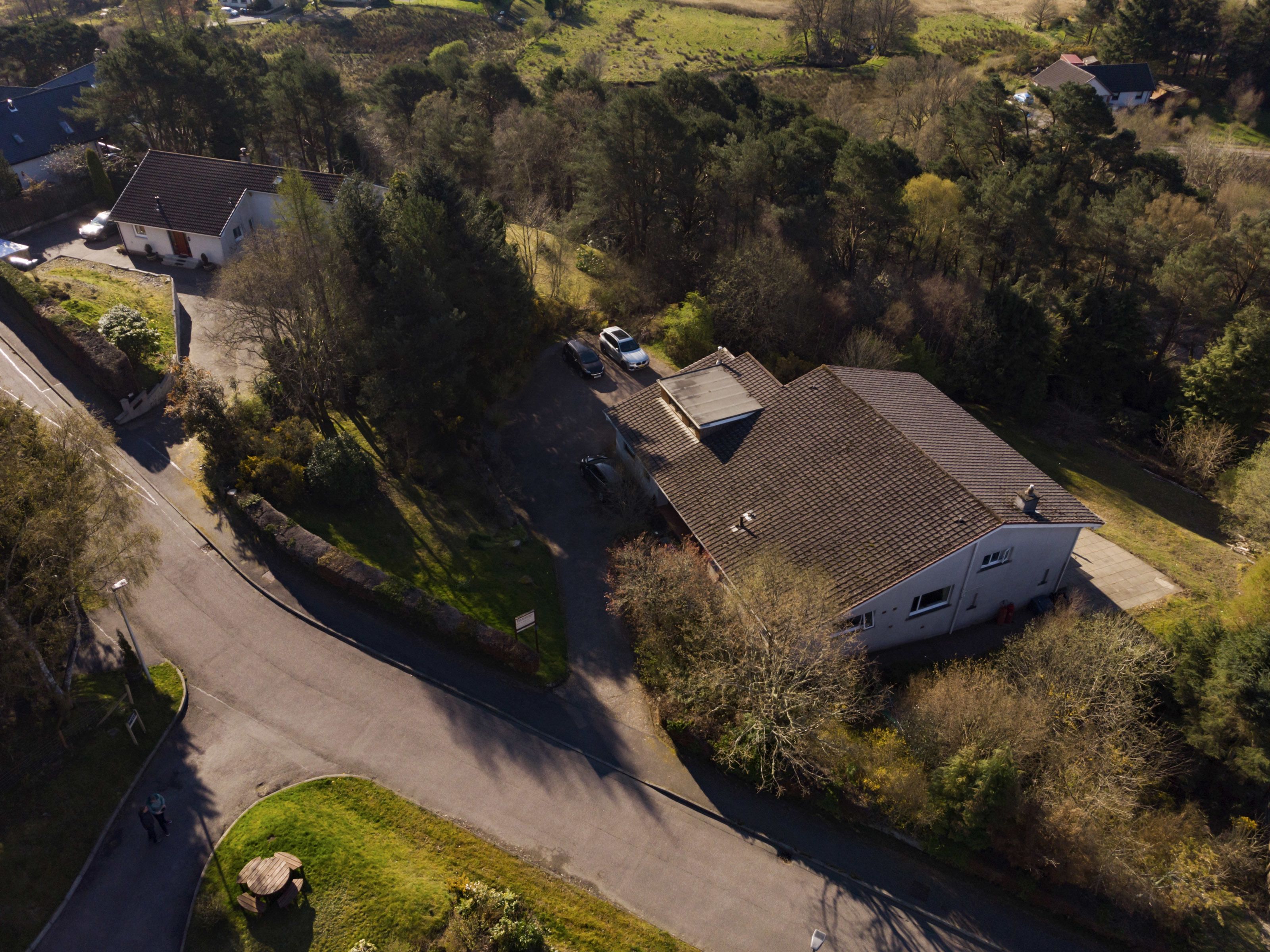 An aerial view of a residential area with houses, a road, and greenery.
