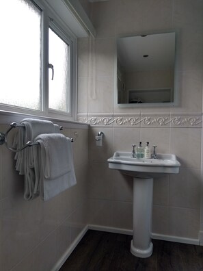 Bathroom features a pedestal sink, mirror, and towel rack.