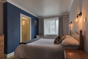 Cozy retreat with a large bed, nightstand, and window with a door to a bathroom.