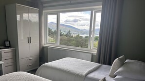 Ein Schlafzimmer mit zwei Betten, einem Kleiderschrank und einem Fenster mit Blick auf die Berge.
