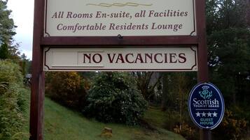 A sign for Braeburn Bed & Breakfast, highlighting stunning views over Loch Linnhe, en-suite rooms, all facilities, a comfortable residents lounge, and no vacancies.