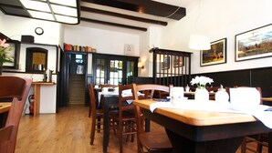 Un accogliente ristorante con arredi in legno, una scala che conduce a una cucina e quadri appesi alle pareti.