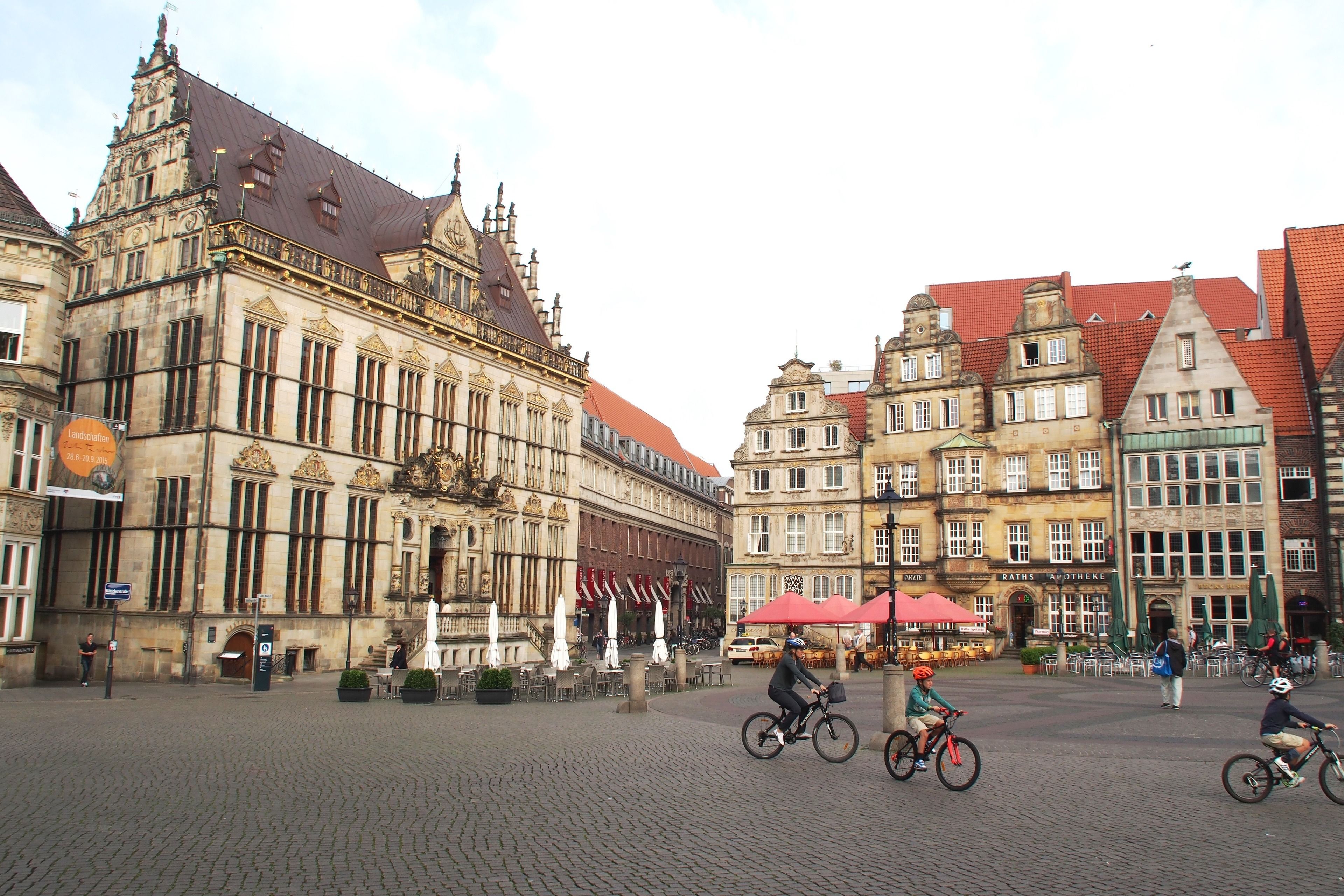 A historic building with ornate architecture, a cobblestone plaza, and outdoor seating areas.