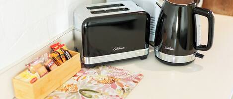 A kitchen with a toaster, a coffee maker, and a wooden box of snacks.
