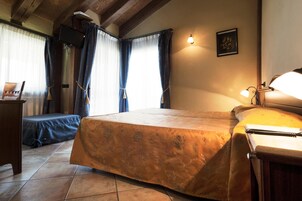 Un dormitorio con cama, escritorio, silla y ventana con cortinas.