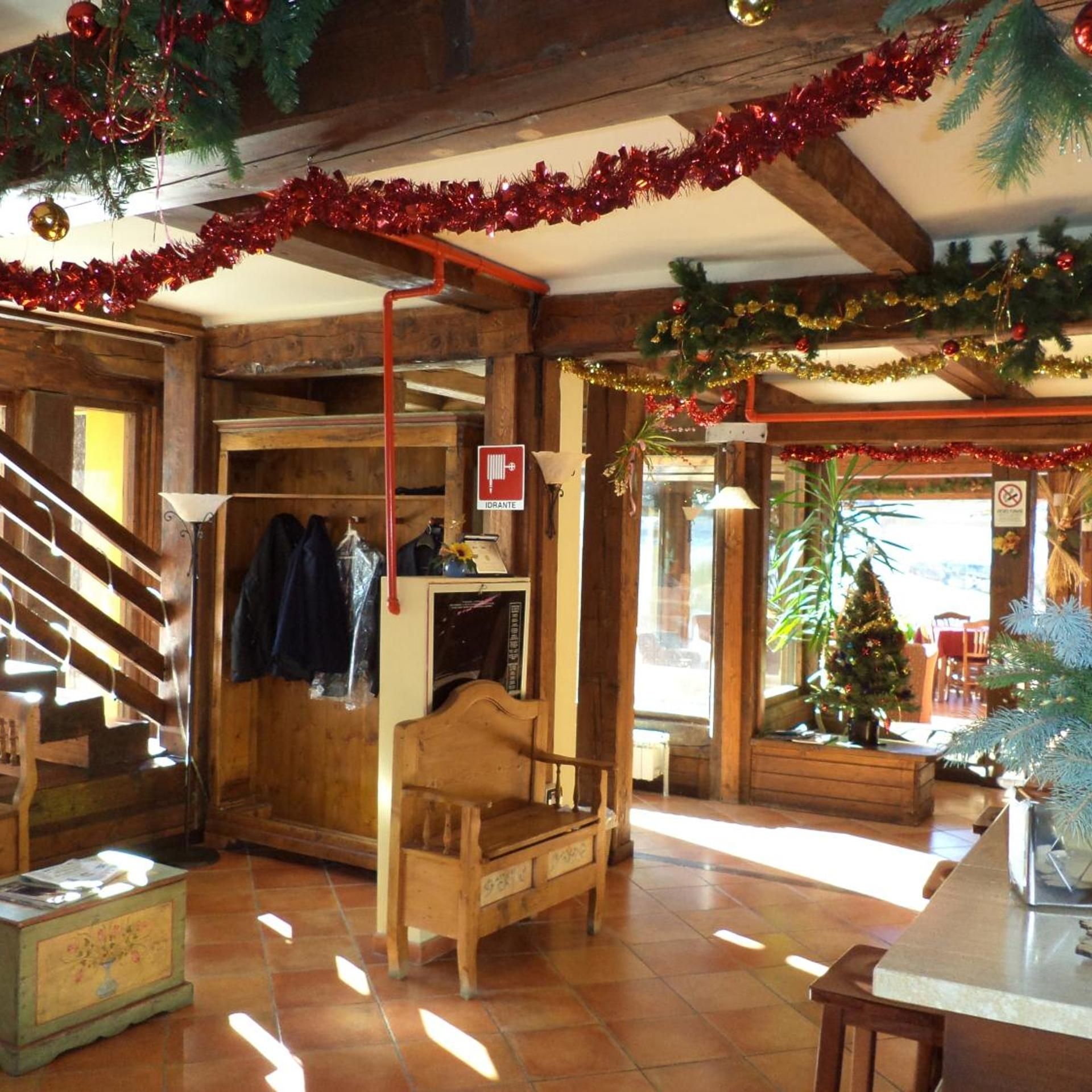 Un intérieur en bois avec un escalier, un banc, une petite table et un sapin de Noël.