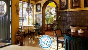 A traditional Thai room with wooden furniture, a dining table with teapots, and a large window with blinds. - Old Capital Bike Inn (Bangkok)