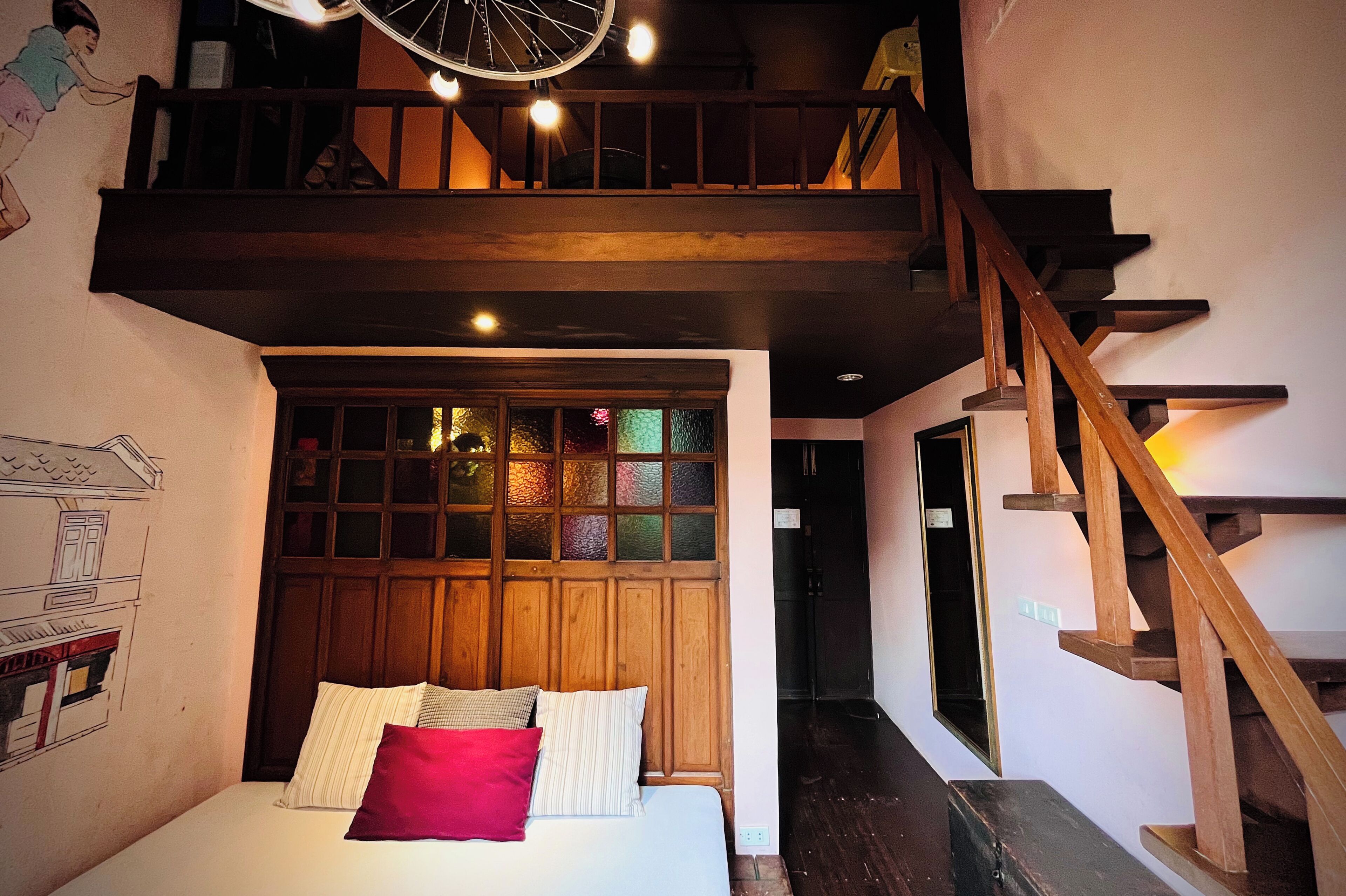 Un dormitorio con cama, ventana con vistas, escalera y lámpara en el techo.