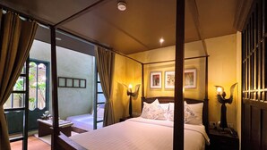A four-poster bed with a canopy, a nightstand with a lamp, and a view of the outdoors through a glass door. - Old Capital Bike Inn (Bangkok)