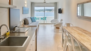 Una cocina moderna con un ventanal grande, una zona de comedor con mesa y sillas de madera, y un sofá con cojines.