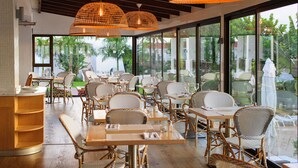 A restaurant with wicker furniture, large windows, and hanging wicker lamps. - Sunprime Atlantic View Suite & Spa (San Bartolomé de Tirajana)