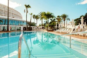 A swimming pool with lounge chairs and palm trees. - Sunprime Atlantic View Suite & Spa (San Bartolomé de Tirajana)