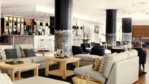 A modern interior with sofas, tables, and a bar area. - Sunprime Atlantic View Suite & Spa (San Bartolomé de Tirajana)