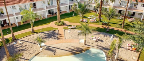 Ein Resort mit Swimmingpool, Palmen und Strand.