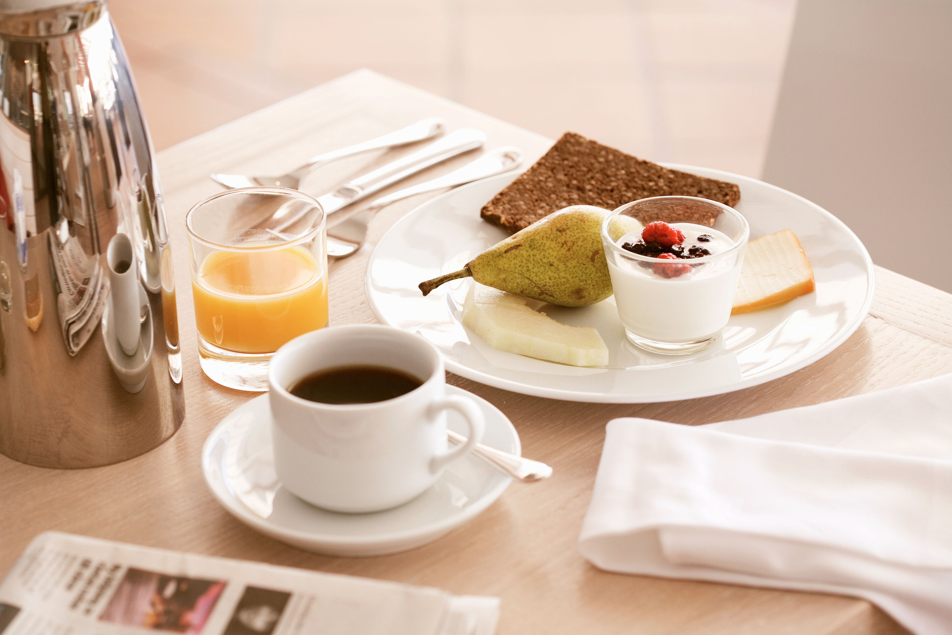 A breakfast setting with a plate of food, a cup of coffee, and a glass of orange juice.