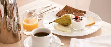 A breakfast setting with a plate of food, a cup of coffee, and a glass of orange juice.