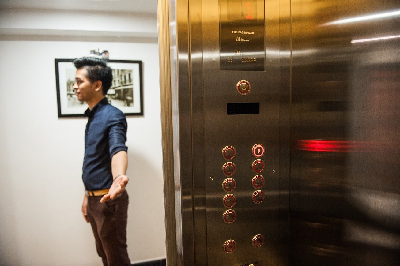 A man standing next to an elevator with a control panel and a door.