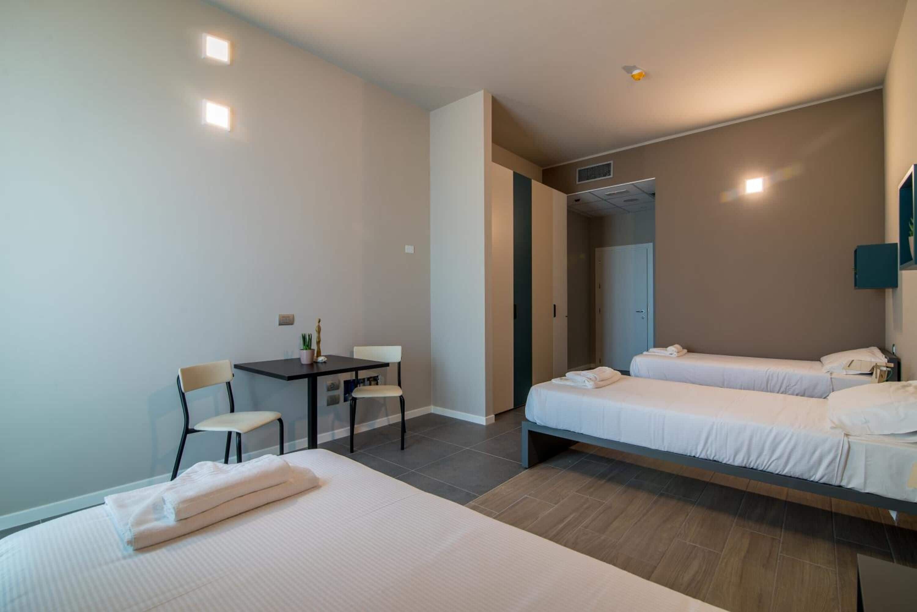 Ett hotellrum med två sängar, ett skrivbord och en stol.