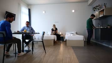 Una habitación moderna y bien iluminada con comedor, sofá y cama.