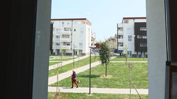 Vista a través de una ventana de un edificio de varios pisos, un área con césped y una persona caminando.