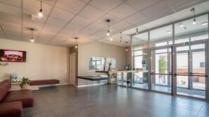 A spacious lobby with a reception desk, seating area, and large glass doors leading outside. - Casa A Colori Padova (Padova)
