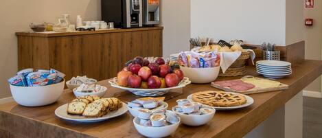 Una mesa de buffet con diversos alimentos, como frutas, pasteles y salsas.
