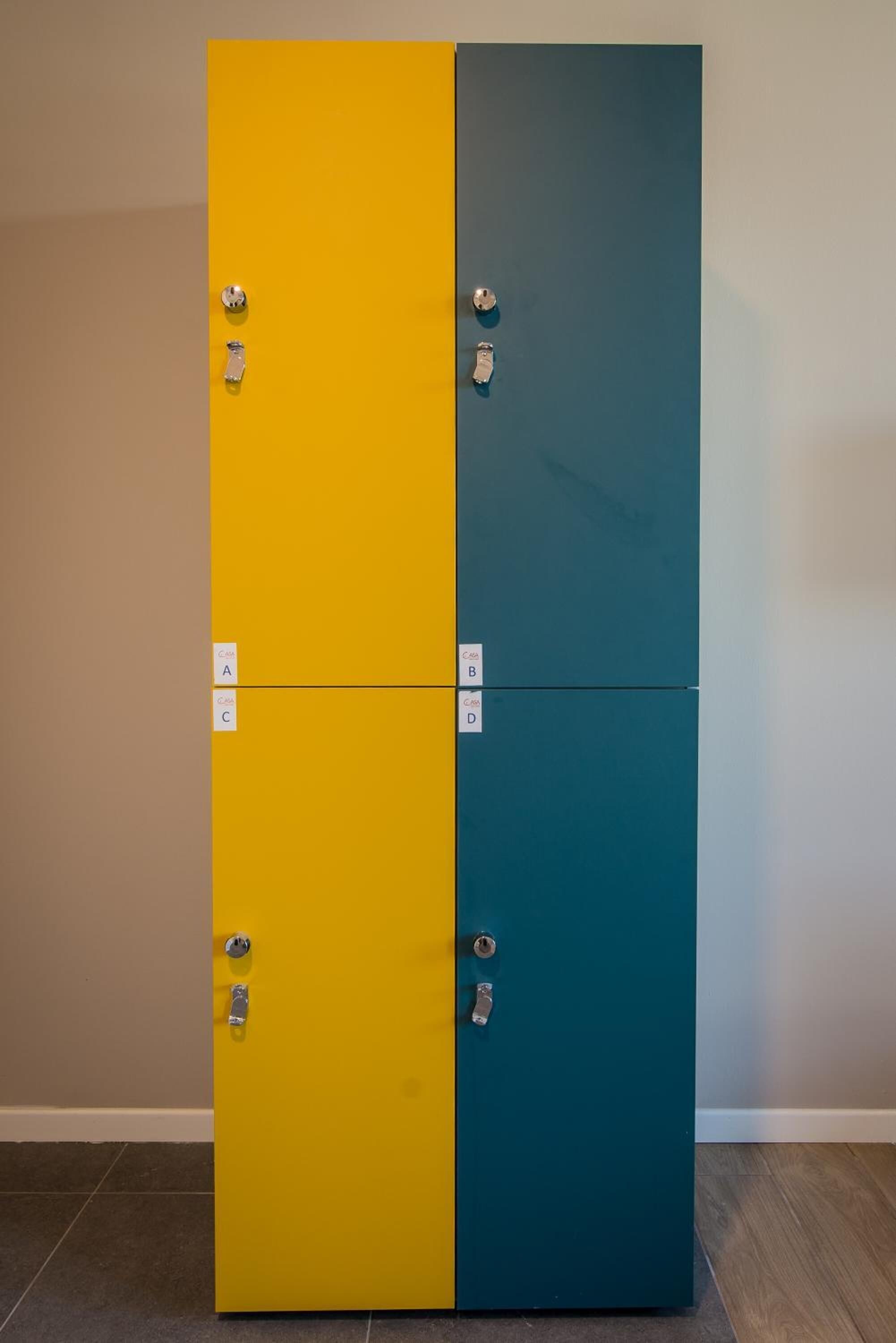 Un meuble à deux portes aux couleurs jaune et turquoise, chaque porte étant marquée d’une lettre.