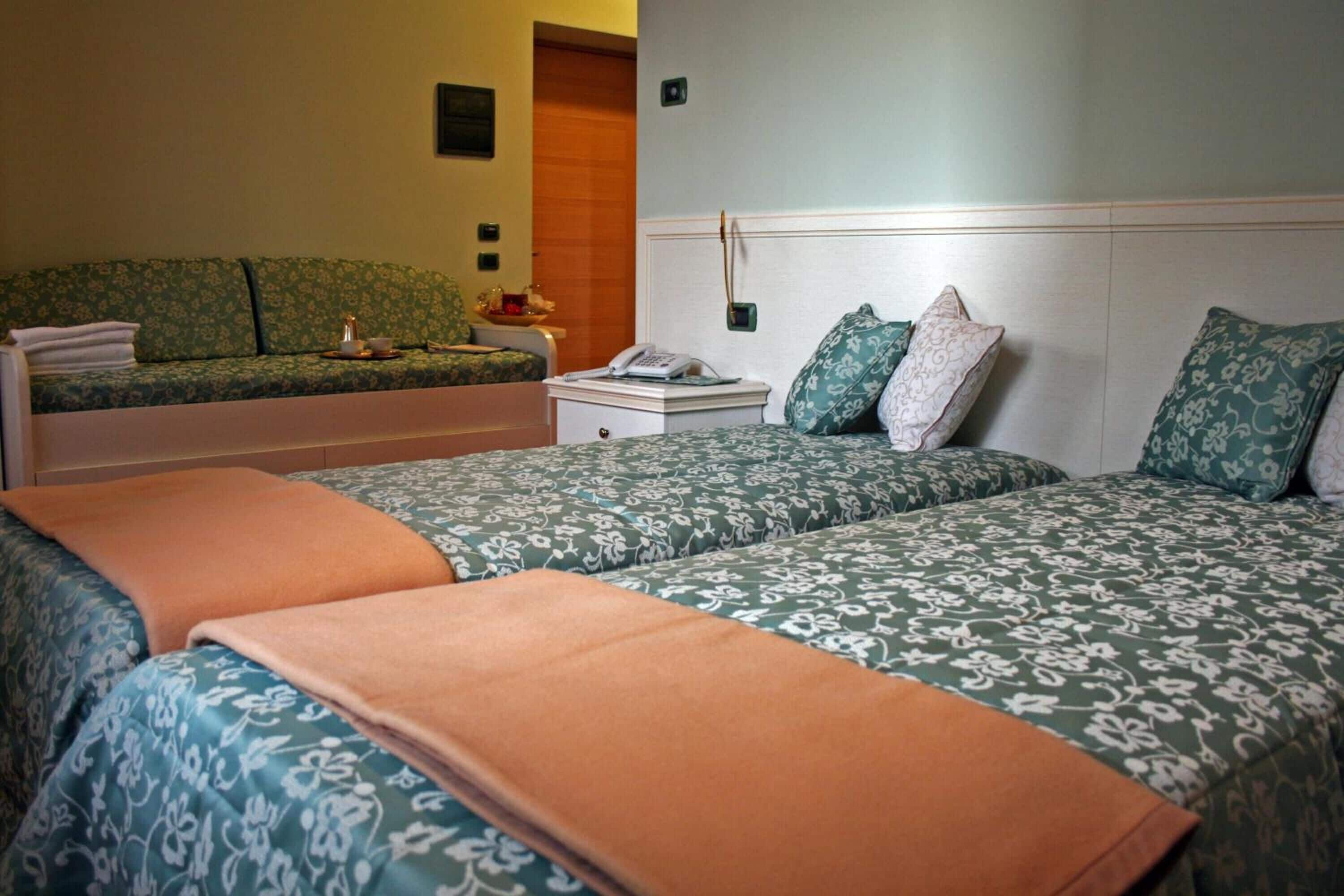 Une chambre d’hôtel avec deux lits, une table de chevet, un téléphone et une petite table avec une lampe.