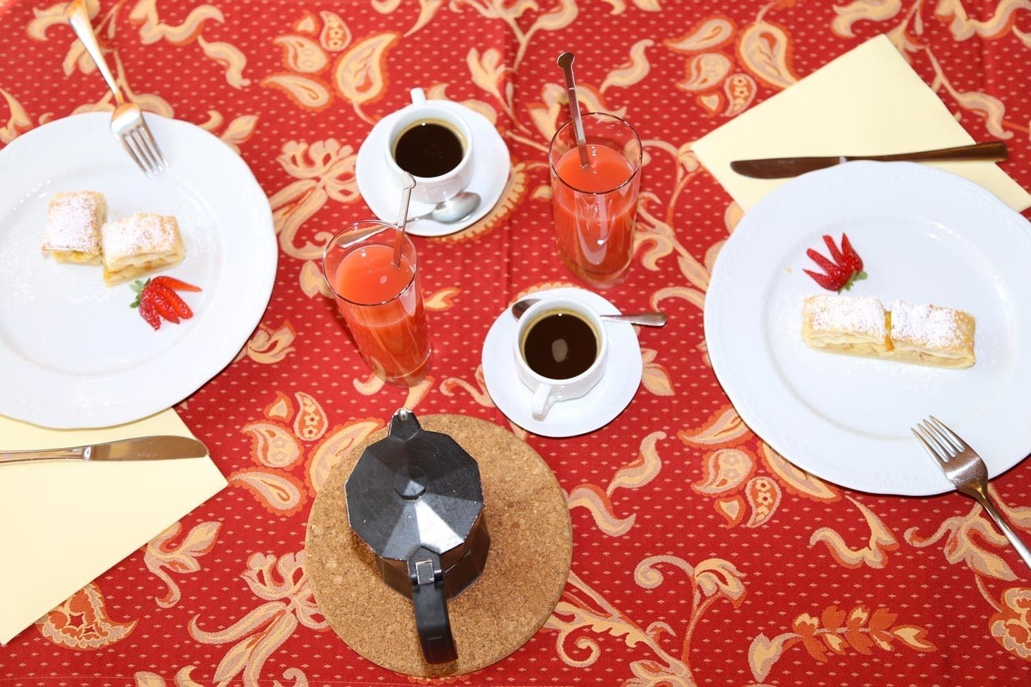 Une table dressée avec des assiettes remplies de nourriture, des tasses de café et une cafetière.