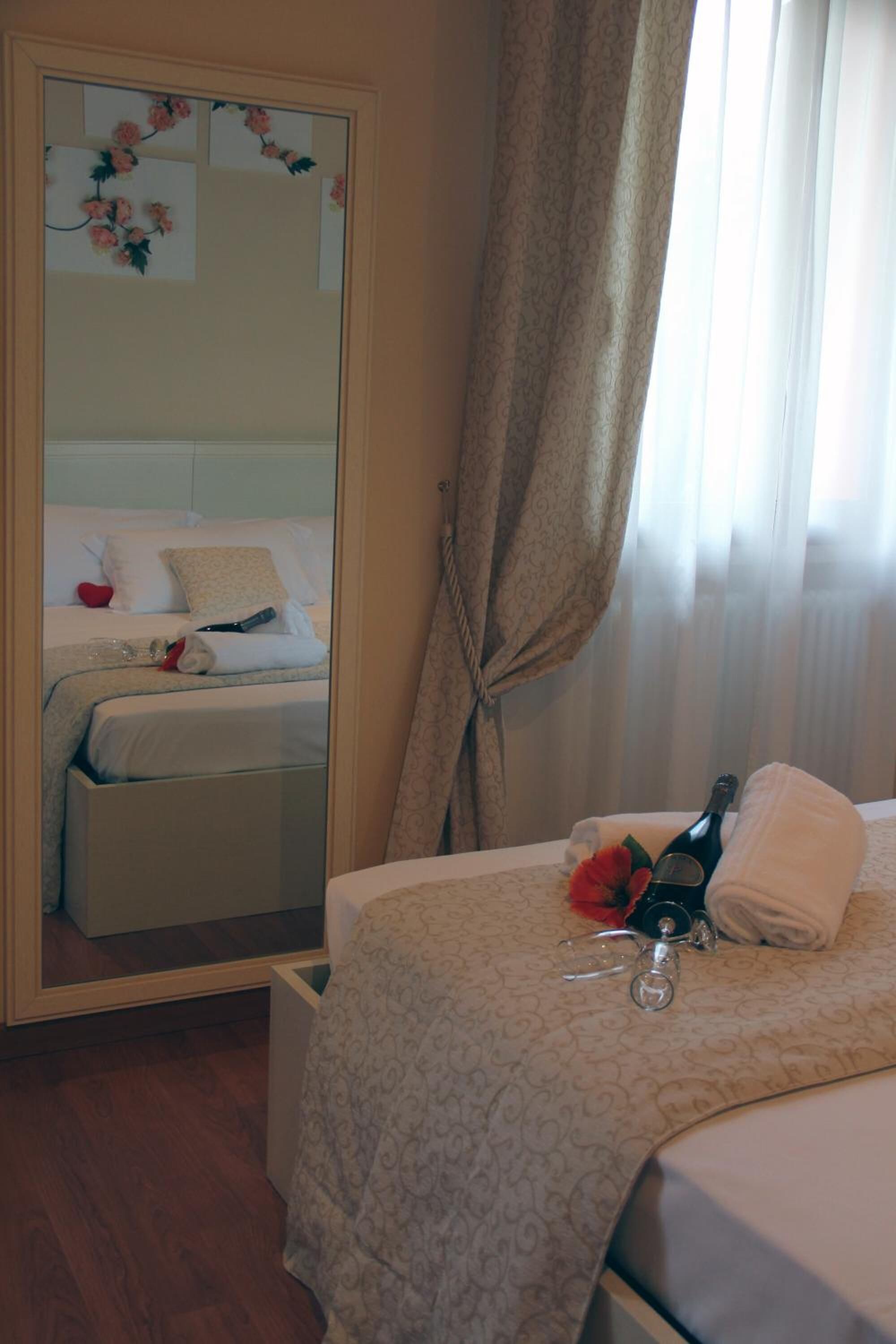 Habitación de hotel con una cama, espejo, botella y toalla.