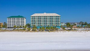 A beachfront hotel with multiple floors, balconies, and a pool area. - Holiday Terrace Beachfront Hotel, a By The Sea Resort (Panama City Beach)